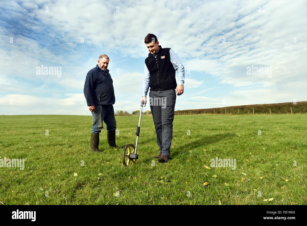 Un rematador encuestas algunas tierras con un agricultor, Milnthorpe, Cumbria Reino Unido Foto de stock