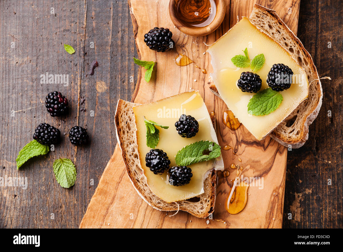 Sándwich con queso y blackberry en pan fresco sobre fondo de madera oscura. Foto de stock