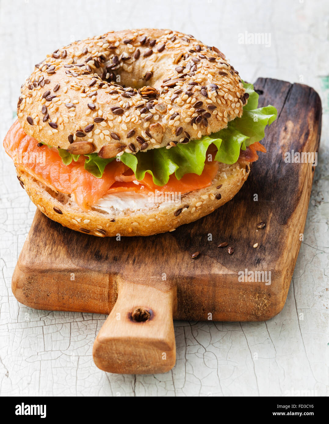 Sandwich bagel de salmón con queso crema y grano en azul de fondo de madera Foto de stock