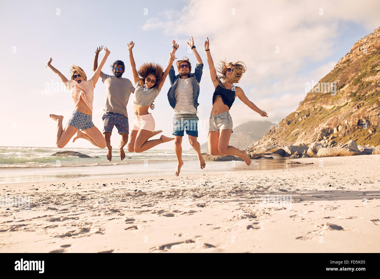 Grupo de amigos en la playa divirtiéndose. Los jóvenes feliz saltando sobre la playa. Grupo de amigos disfrutando del verano vac Foto de stock