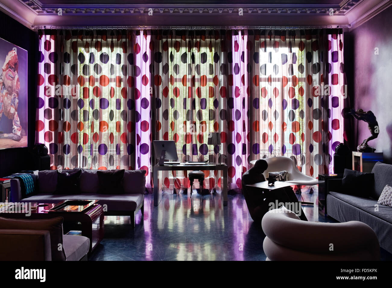 En la ventana Escritorio retroiluminados con rojo y púrpura manchada de cortinas y luces de neón azul, London apartment Foto de stock