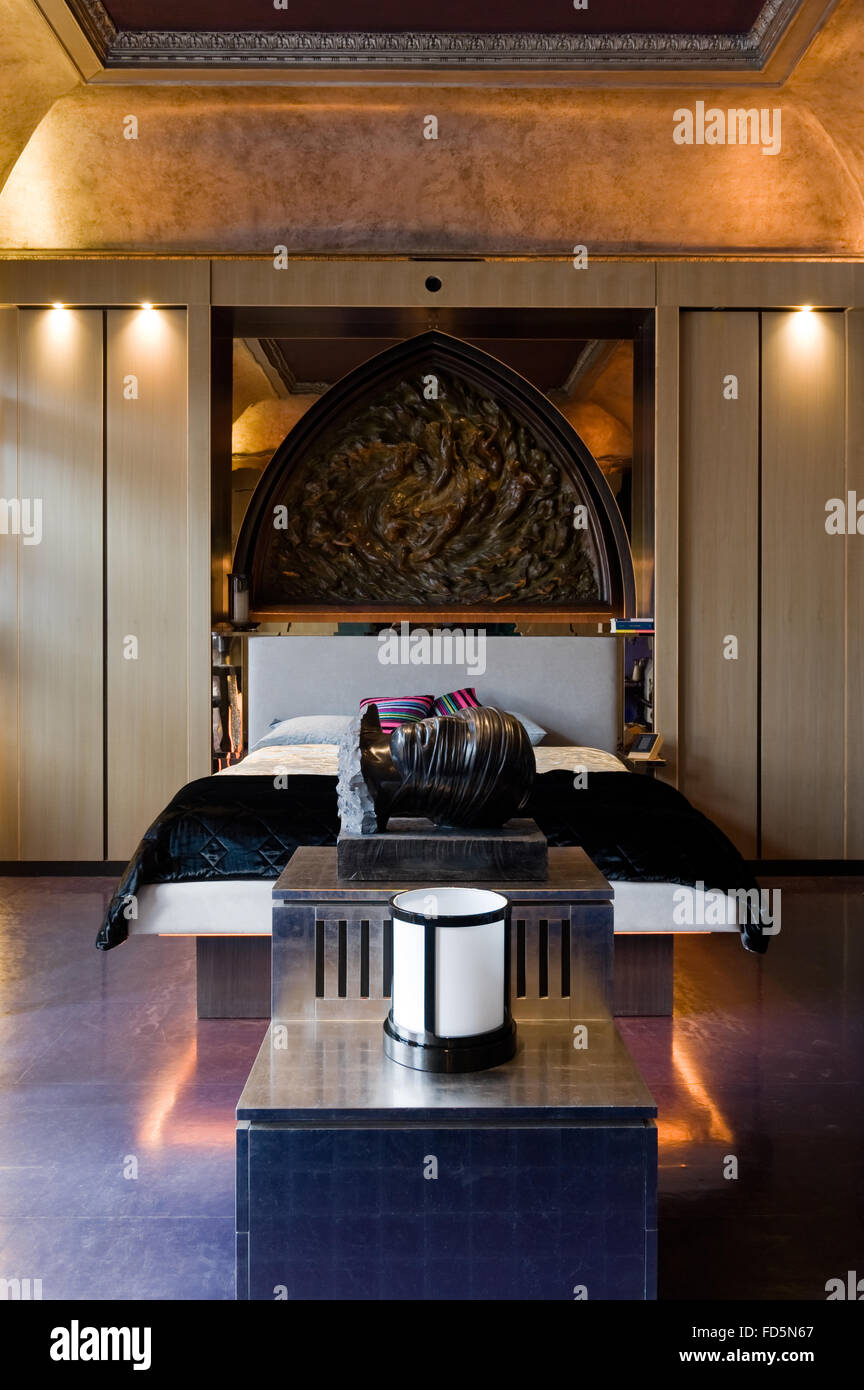 Arco apuntado de bronce encima de cama doble con cabeza caídos en Londres apartamento Foto de stock