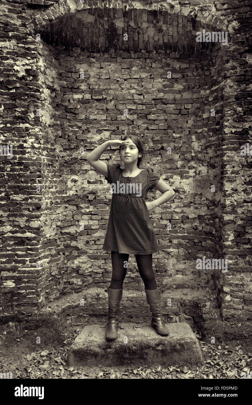 Adolescente actuando como una dama en el pasado de pie en frente de las ruinas de su castillo Foto de stock