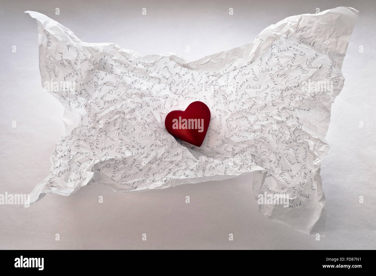 Un corazón rojo en un fondo de papel tisú blanco arrugado que se ha inscrito con 'Cariad', la palabra galesa para 'amor'. Foto de stock
