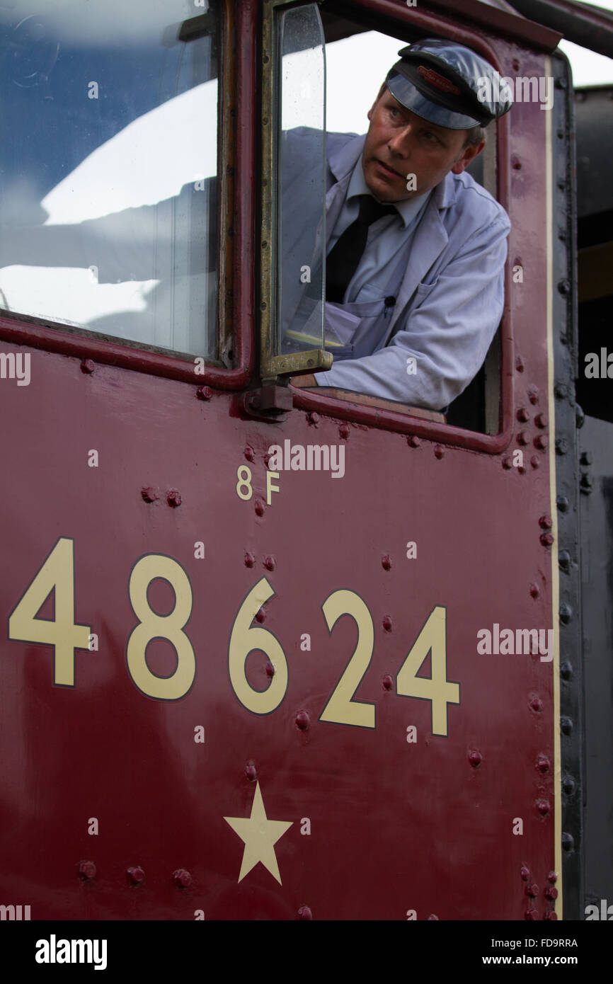 Conductor de Tren en 8F 48624 comienza su lejos de la estación de tren con una expresión facial que muestra la concentración, la gran línea de ferrocarril central, Loughborough. Foto de stock