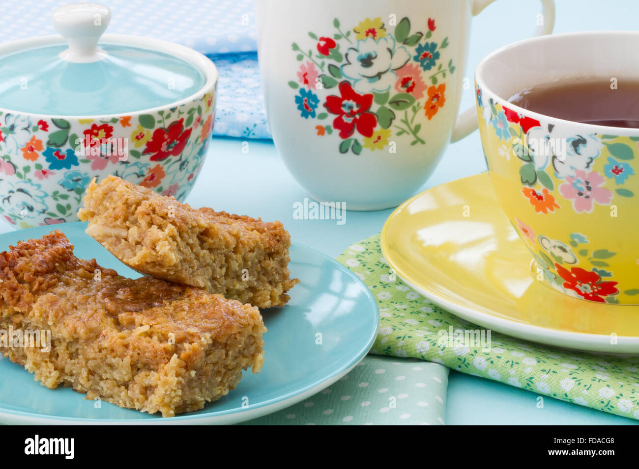 El té de la tarde o de un delicioso té de pastel y una taza de té en la vajilla floral. flapjack y té en una taza y plato florecido como snack Foto de stock