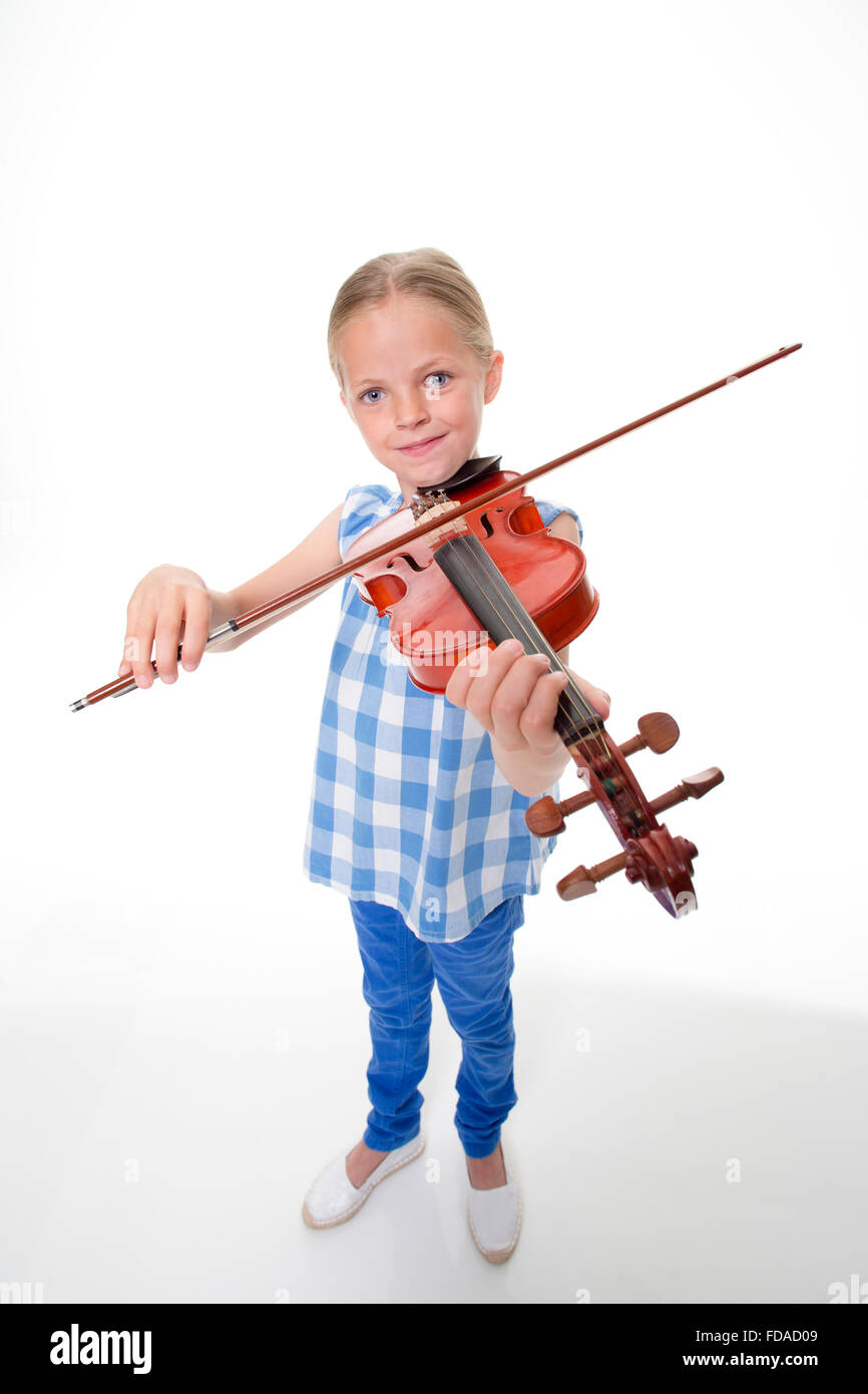 Niña jugando un violín sobre un fondo blanco. Ella está mirando a la cámara y sonriendo. Foto de stock