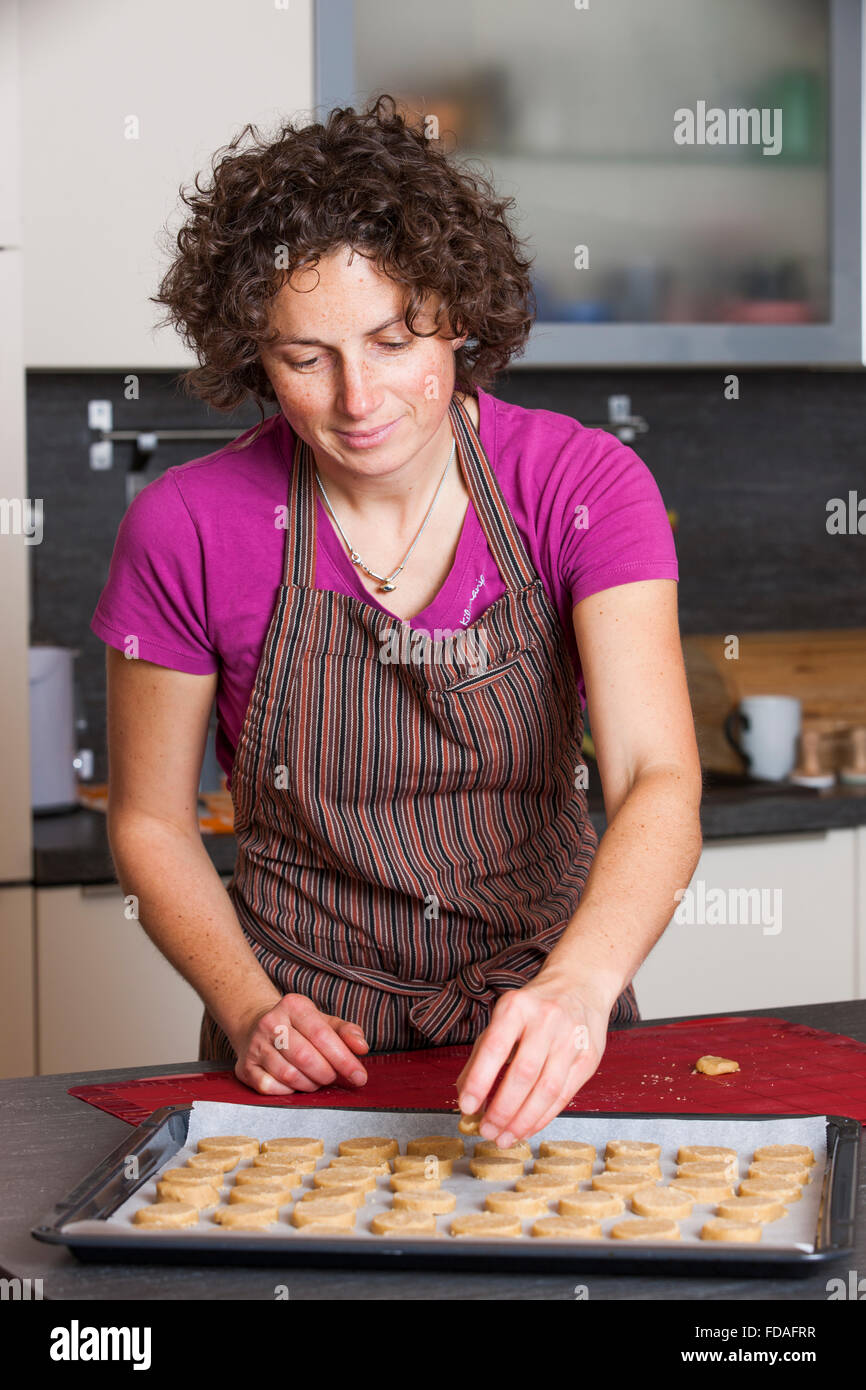 Mujer poniendo la masa de galleta en la hoja de hornear Foto de stock