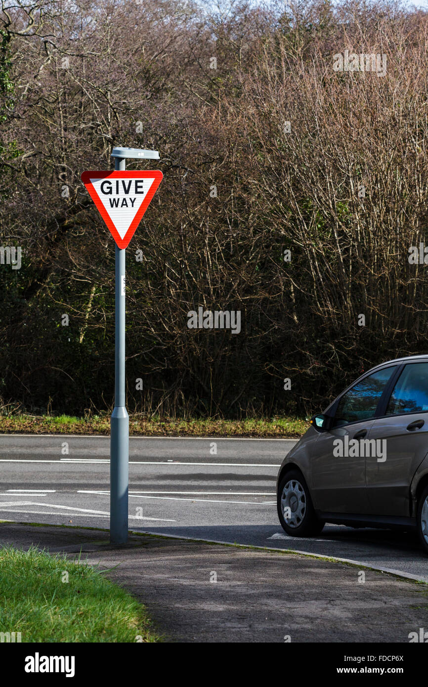 Una forma de dar señales de carretera con un coche parado inmóvil en la intersección. Foto de stock