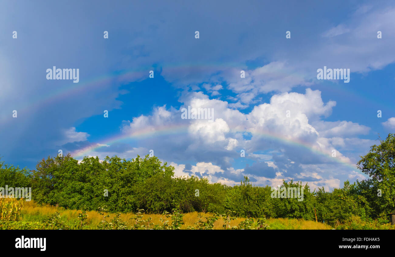 Paisaje de verano con doble arco iris, verde hierba, aldeas, campos y bellas nubes, Donbass Foto de stock