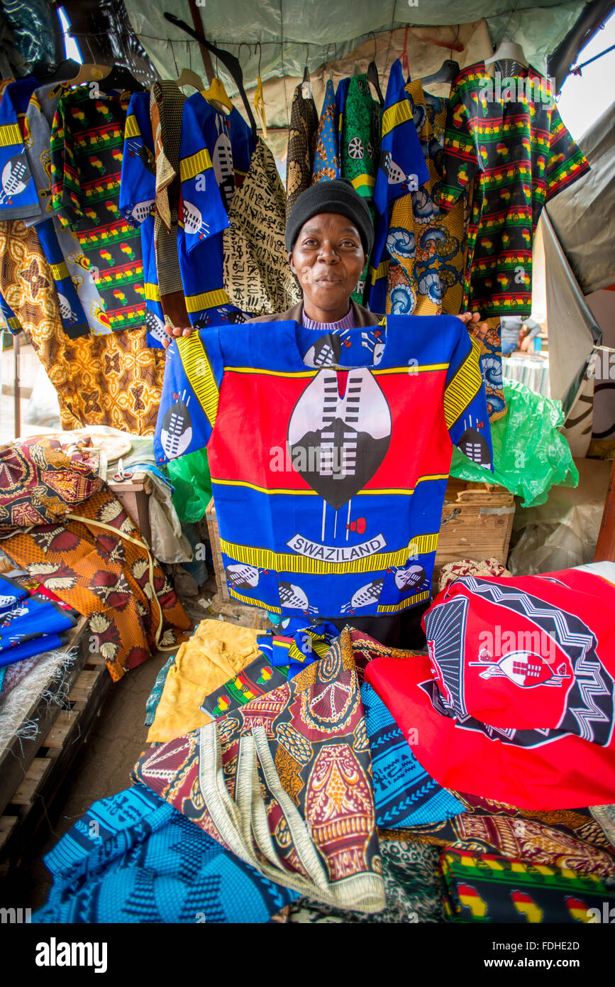 Mujer Africana vendiendo camisetas estampadas en el mayorista de Manzini producir y el Mercado Artesanal en Suazilandia, África Foto de stock