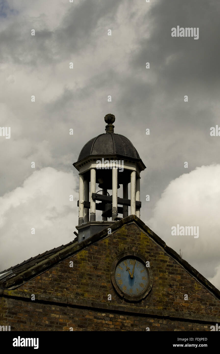 La campana y el reloj en el exterior en Quarry Bank Mill, Styal, Cheshire. El molino fue fundada en 1784 y produjo el algodón hasta el 1950. Foto de stock