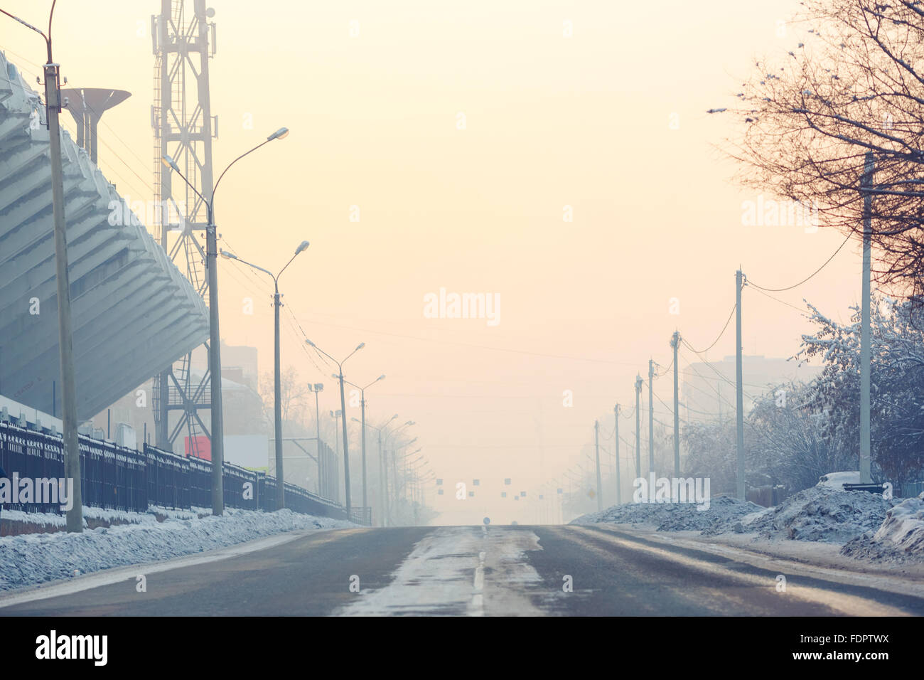 Los antecedentes, la carretera en una calle vacía en la ciudad en días fríos de invierno cubierto de nieve cerca de estadio, la perspectiva aérea. Postes de luz a lo largo de los bordes de la carretera. Foto de stock
