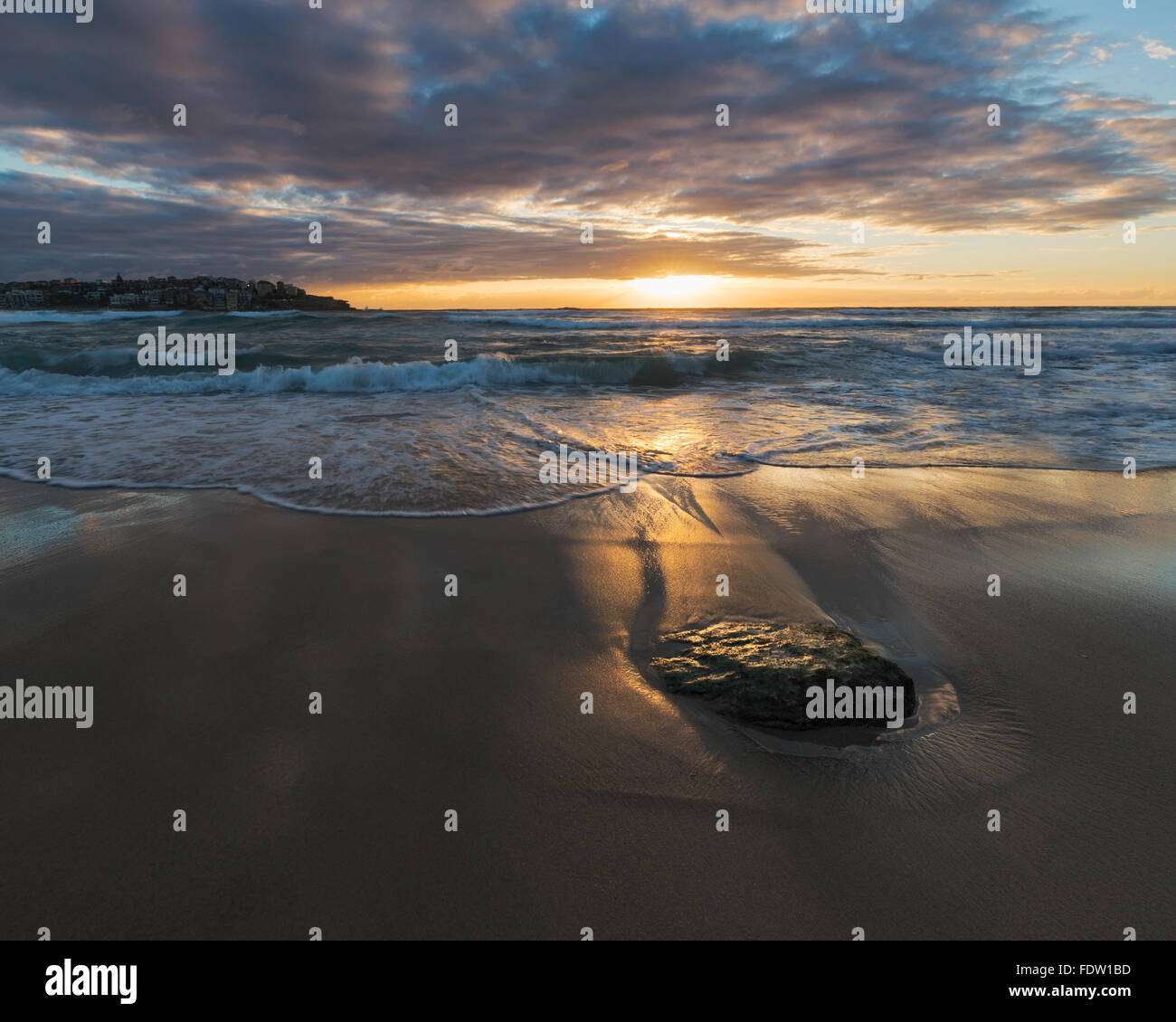 Una agradable mañana en la playa de Bondi con luz cálida y hermosa nubes y un suave oleaje Foto de stock