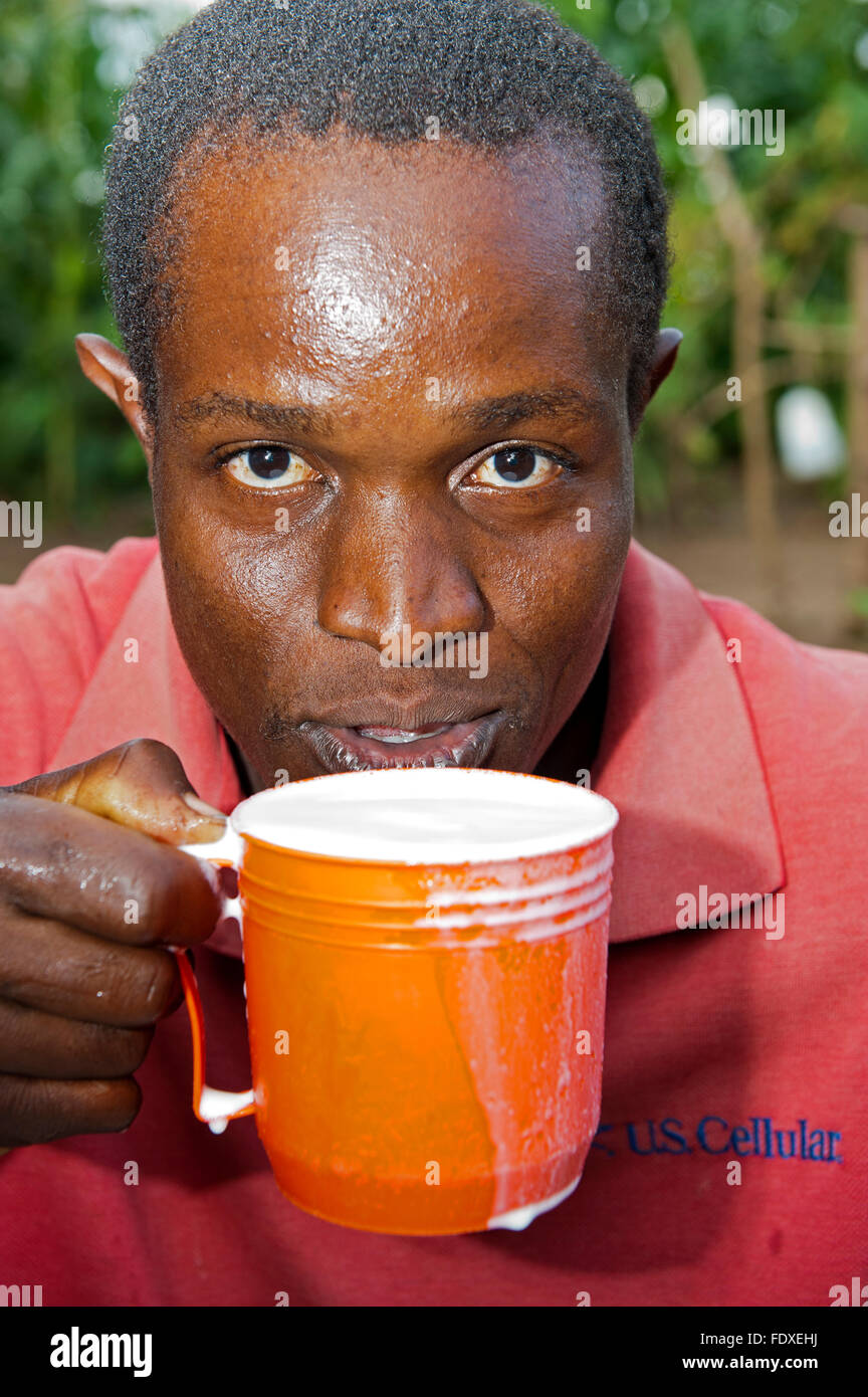 Hombre beber un vaso de leche de vaca fresca, Uganda. Foto de stock
