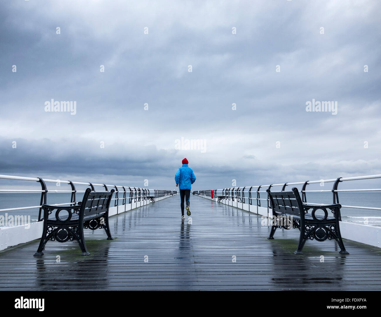 Hombre maduro, trotar en Saltburn pier en la lluvia. Saltburn por el mar. North Yorkshire. UK Foto de stock