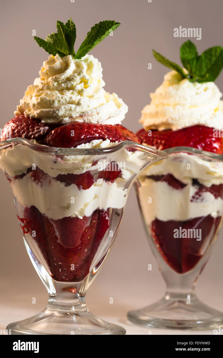 Una vista cercana de fresas frescas marinadas en Puerto con crema Chantilly  en vasos Sundae guarnecida con menta fresca Fotografía de stock - Alamy