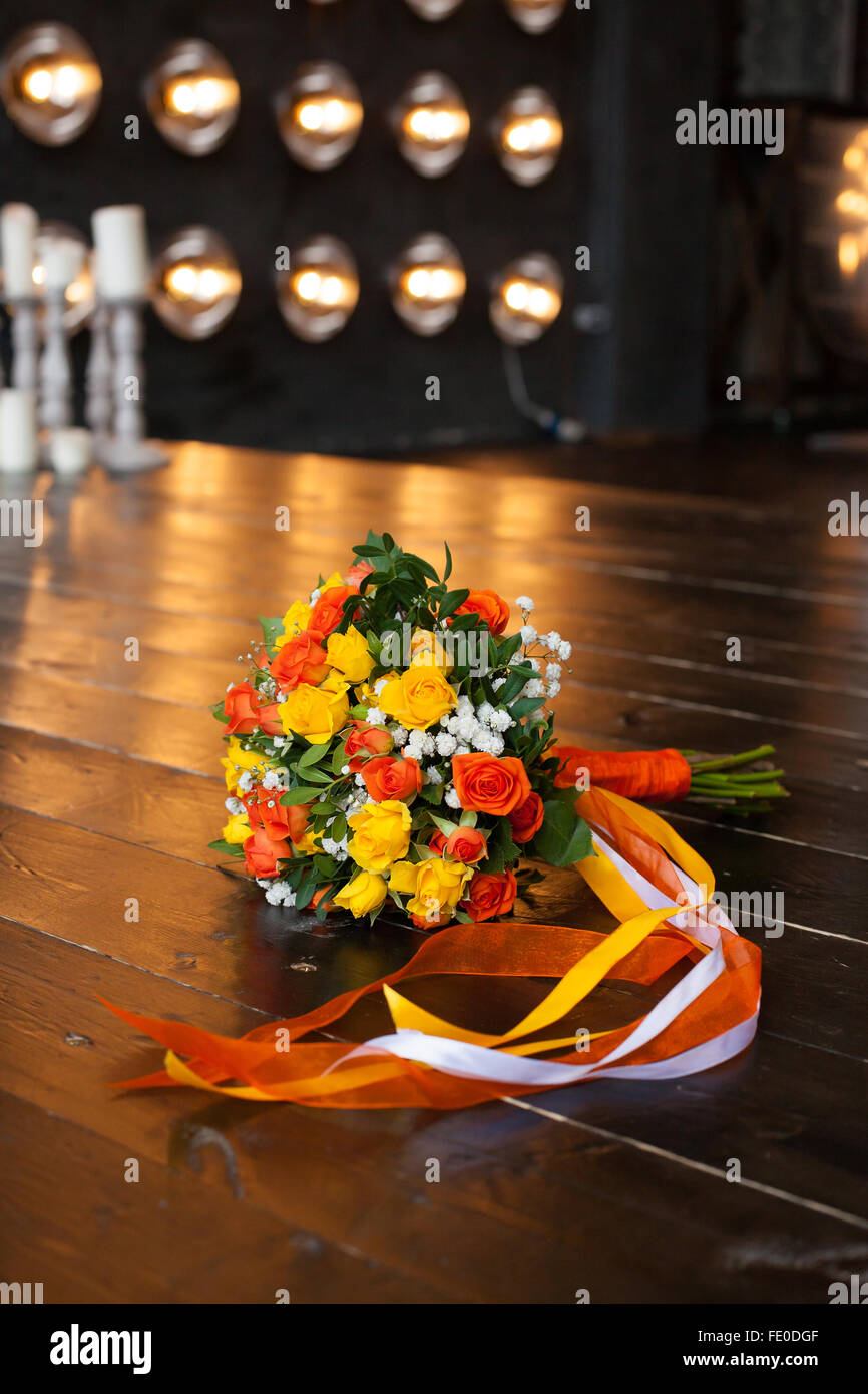 Ramo de novia de amarillo y naranja color de rosas sobre un piso en contra de lámparas y velas Foto de stock