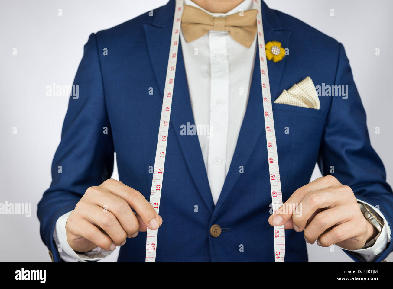 Hombre de traje azul con crema de café pajarita de color, de flor, y el patrón de puntos cuadrados de bolsillo llevar la cinta de medición Fotografía de stock - Alamy