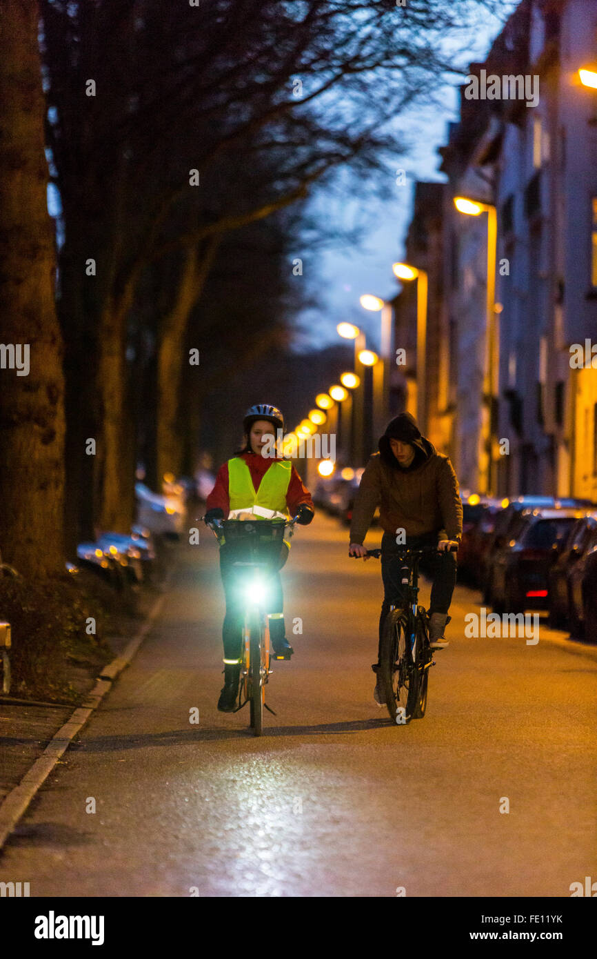 Conducción ciclista, al anochecer, en una calle de la ciudad, con y sin luces y ropa de seguridad, bicicleta de seguridad, visibilidad de noche Foto de stock