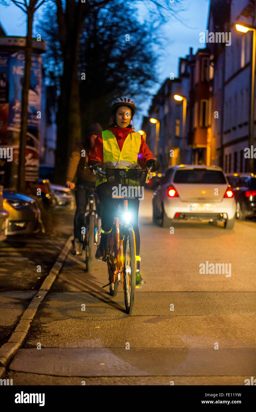 Conducción ciclista, al anochecer, en una calle de la ciudad, con y sin luces y ropa de seguridad, bicicleta de seguridad, visibilidad de noche Foto de stock