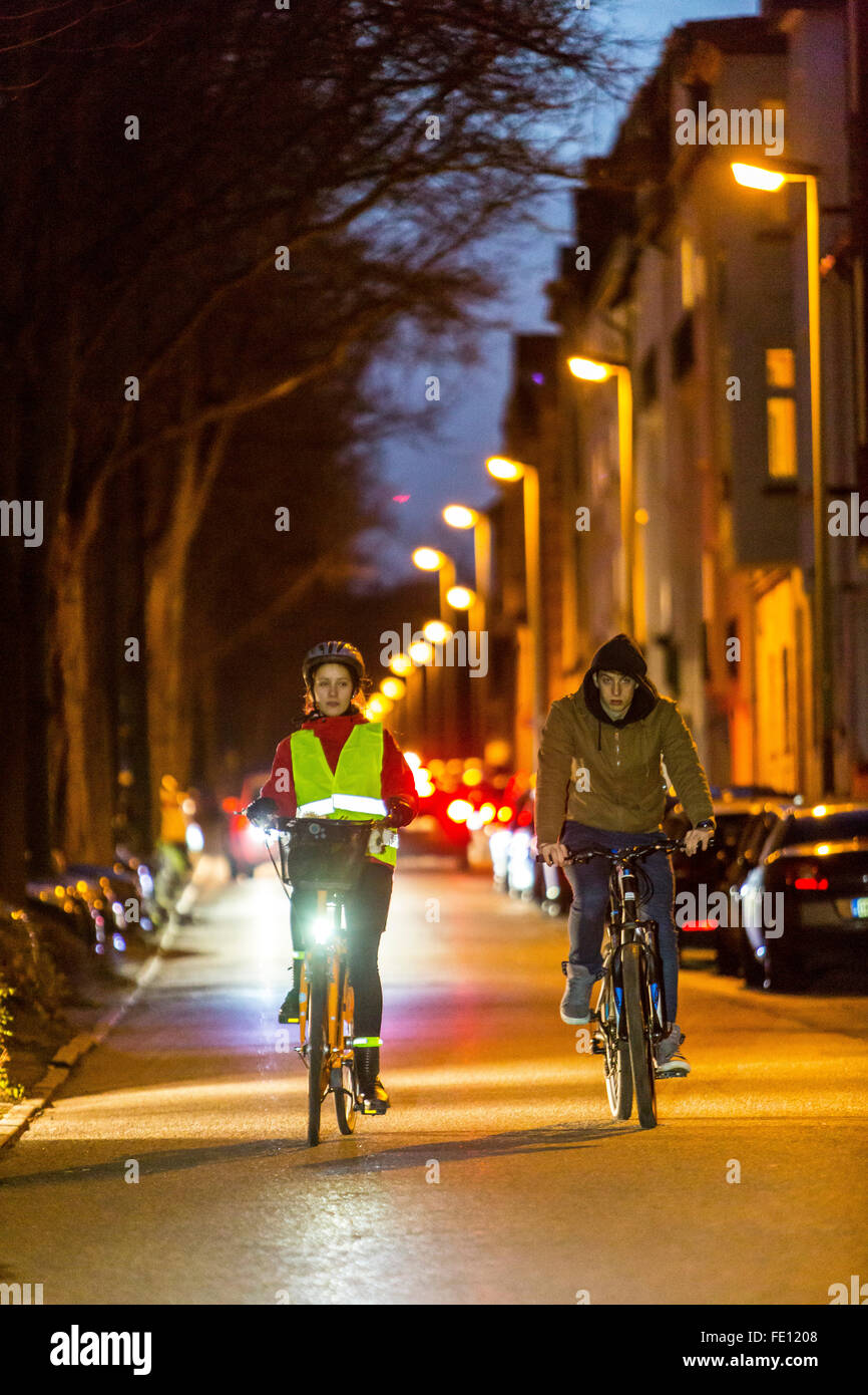 Conducción ciclista, al anochecer, en una calle de la ciudad, con y sin luces y ropa de seguridad, bicicleta de seguridad, visibilidad de noche Foto de stock