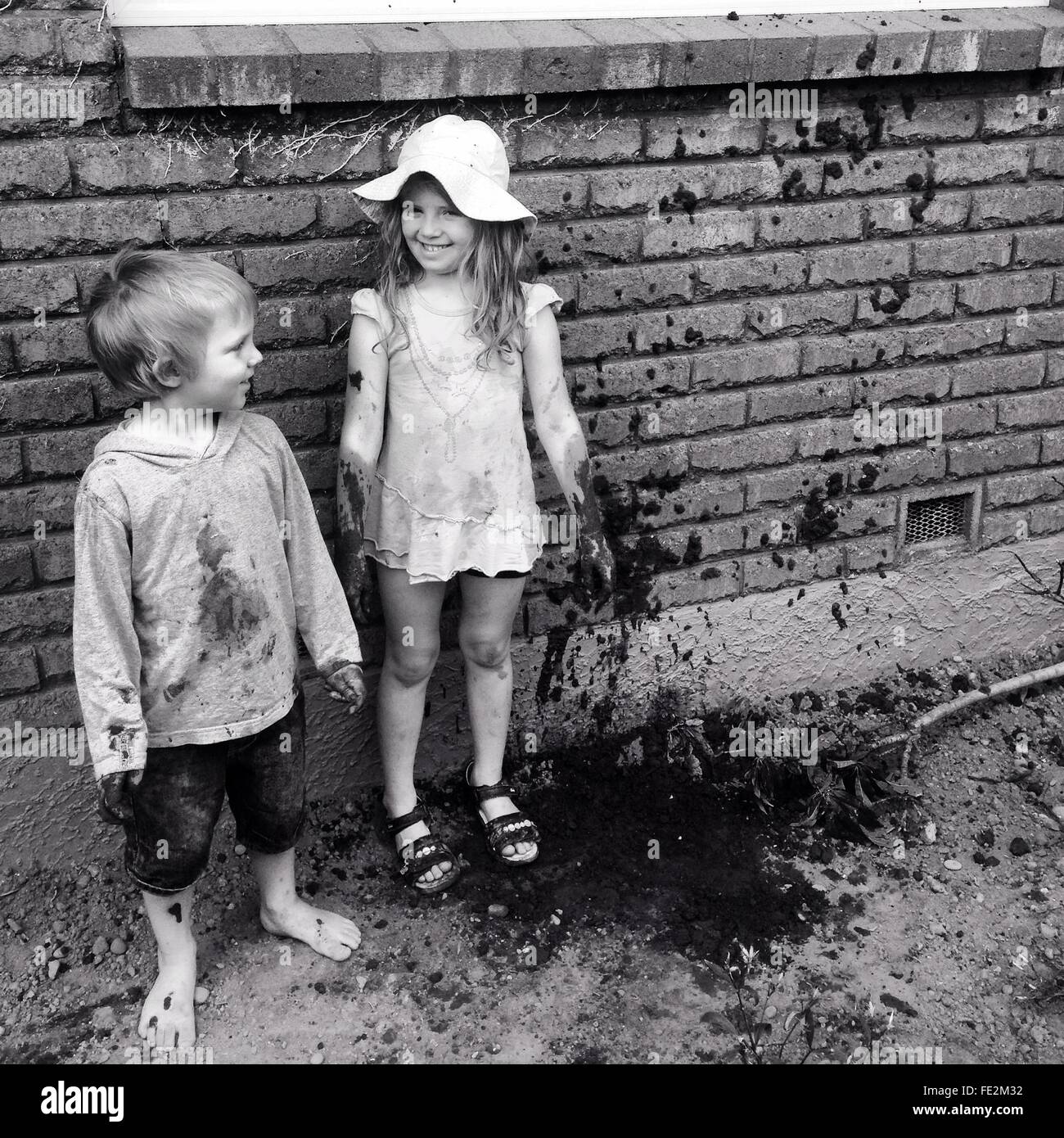 Chico y chica jugando con barro Foto de stock