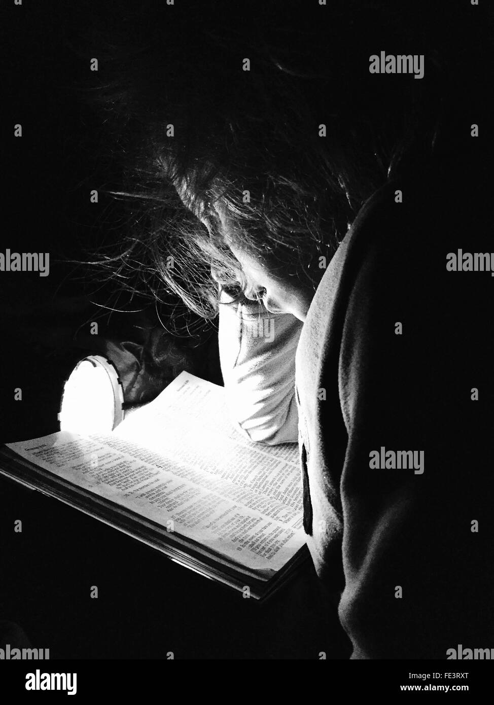 Chica leyendo la Biblia En Linterna en casa Fotografía de stock - Alamy