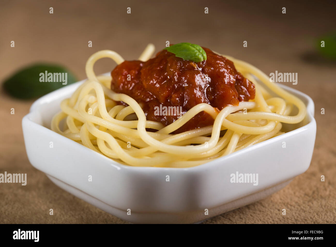 Espaguetis con salsa de tomate y albahaca en un recipiente blanco Foto de stock