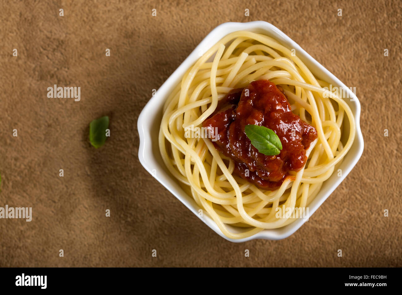 Espaguetis con salsa de tomate y albahaca en un recipiente blanco Foto de stock