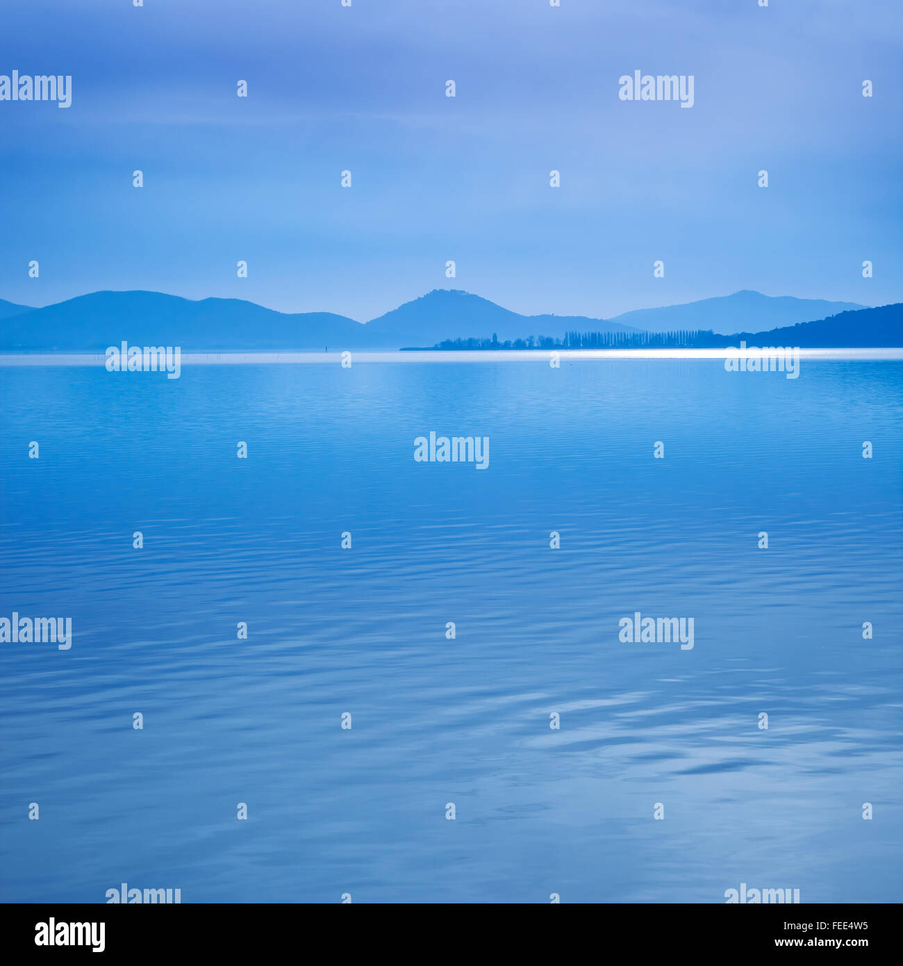 Superficie de agua de un azul mañana sobre el lago Trasimeno, Umbría, Italia. Las colinas en el fondo. Foto de stock