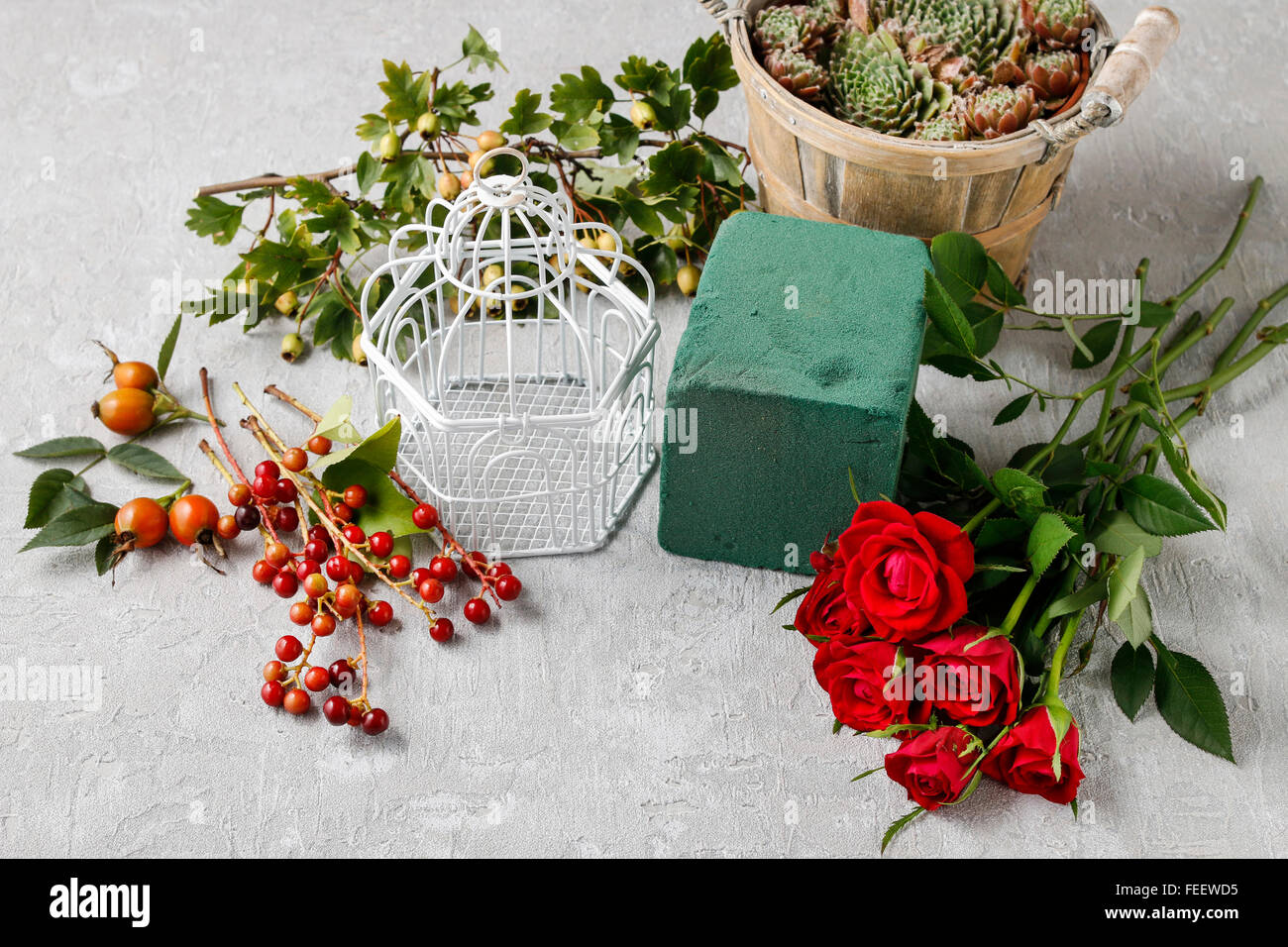 Floristería en el trabajo: cómo hacer arreglos florales con rosas y hawthorn bayas en vintage en forma de jaula. Foto de stock