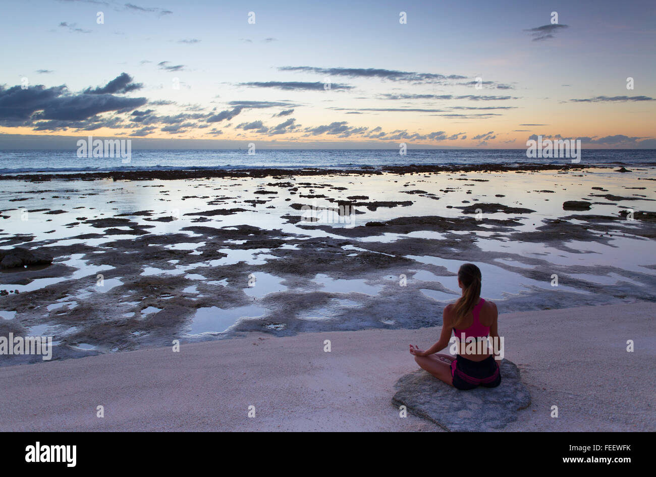 Mujer practicando yoga en la playa al amanecer, Fakarava, las Islas Tuamotu, en la Polinesia Francesa Foto de stock