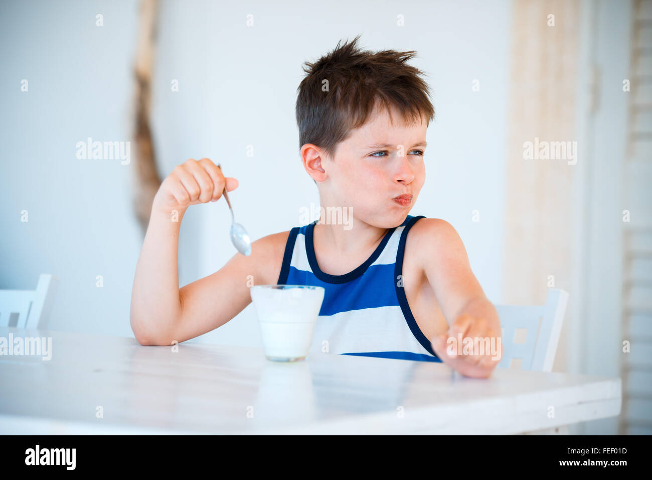 Sonriente niño se niega a comer delicioso yogur Foto de stock