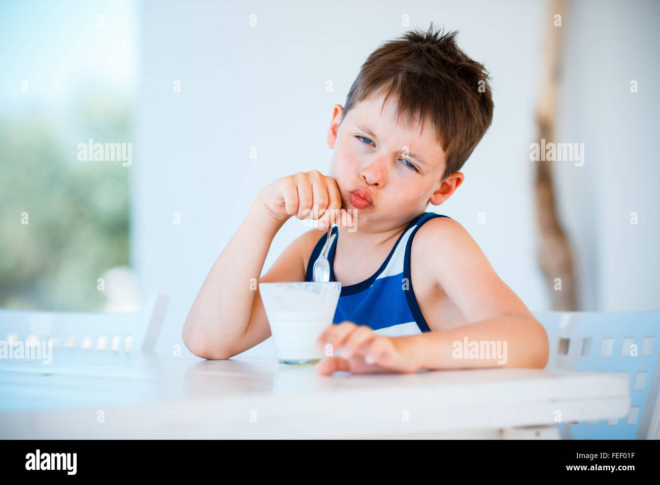 Sonriente niño se niega a comer delicioso yogur Foto de stock