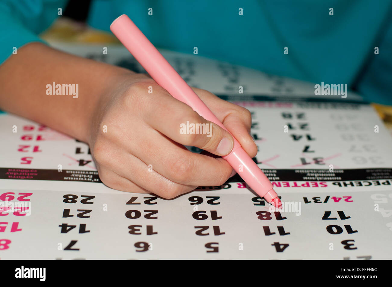 La foto de calendario con un dato marcado por kid's mano con un marcador de color rosa, el concepto de la gestión del tiempo en el trabajo Foto de stock