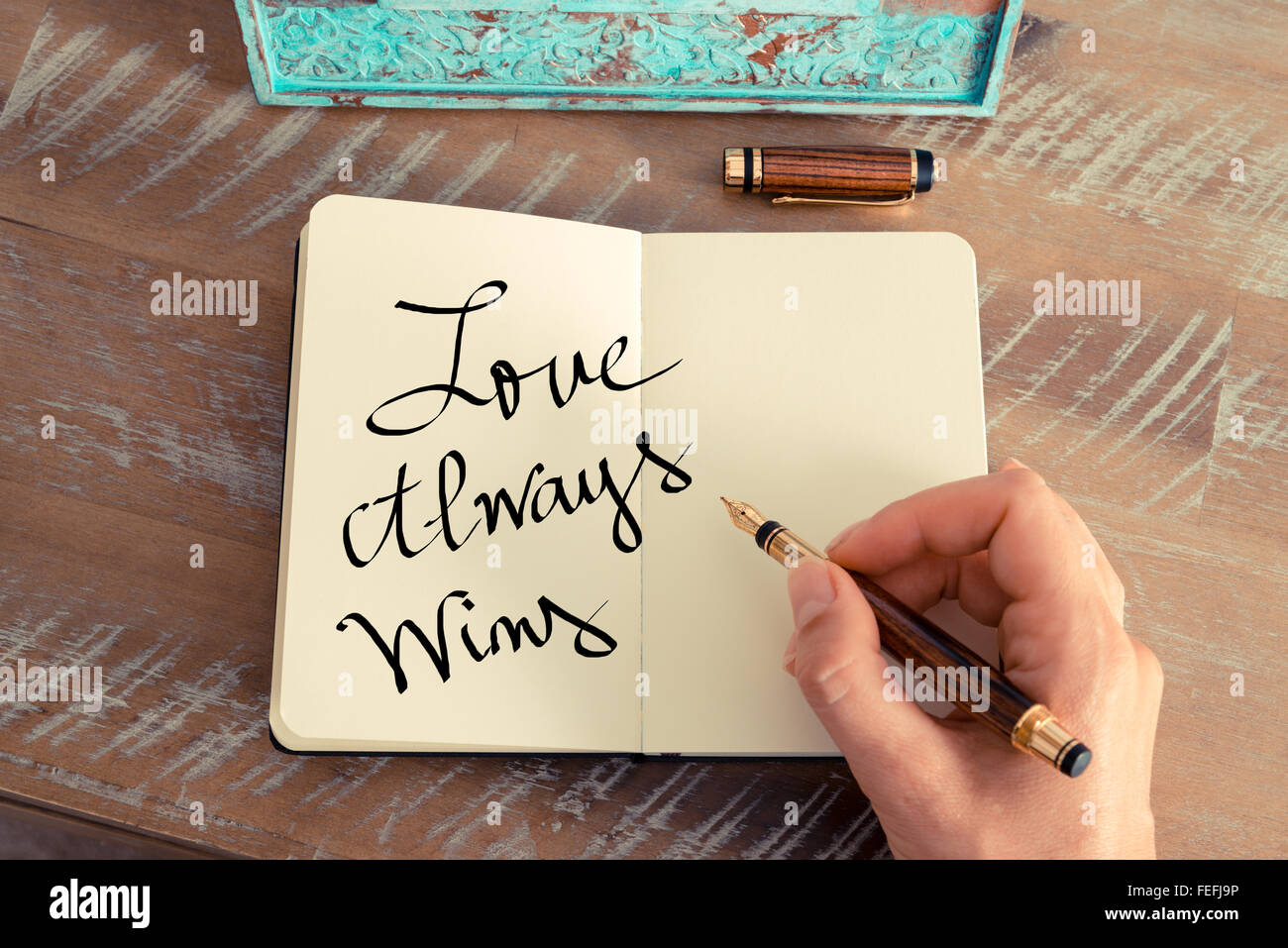 Efecto retro y tonos de la imagen de una mujer escribiendo una nota a mano con una pluma estilográfica en un portátil. Foto de stock