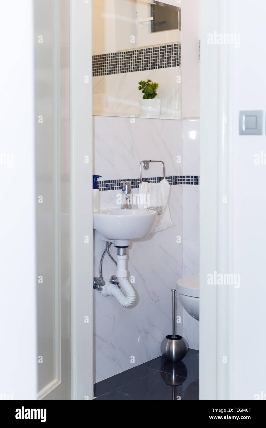 Baño de hotel: fregadero, grifo, toallas y set de baño. Baño moderno diseño interior a la luz de colores brillantes con lavamanos y espejo Foto de stock