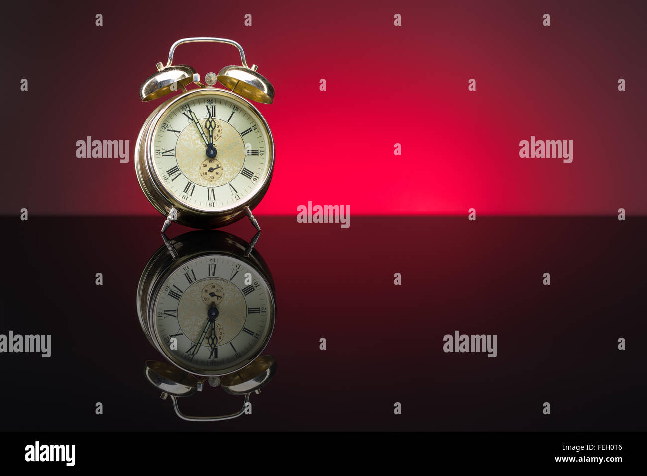 Vintage despertador mostrando cinco minutos a doce, fondo rojo, espacio de copia Foto de stock