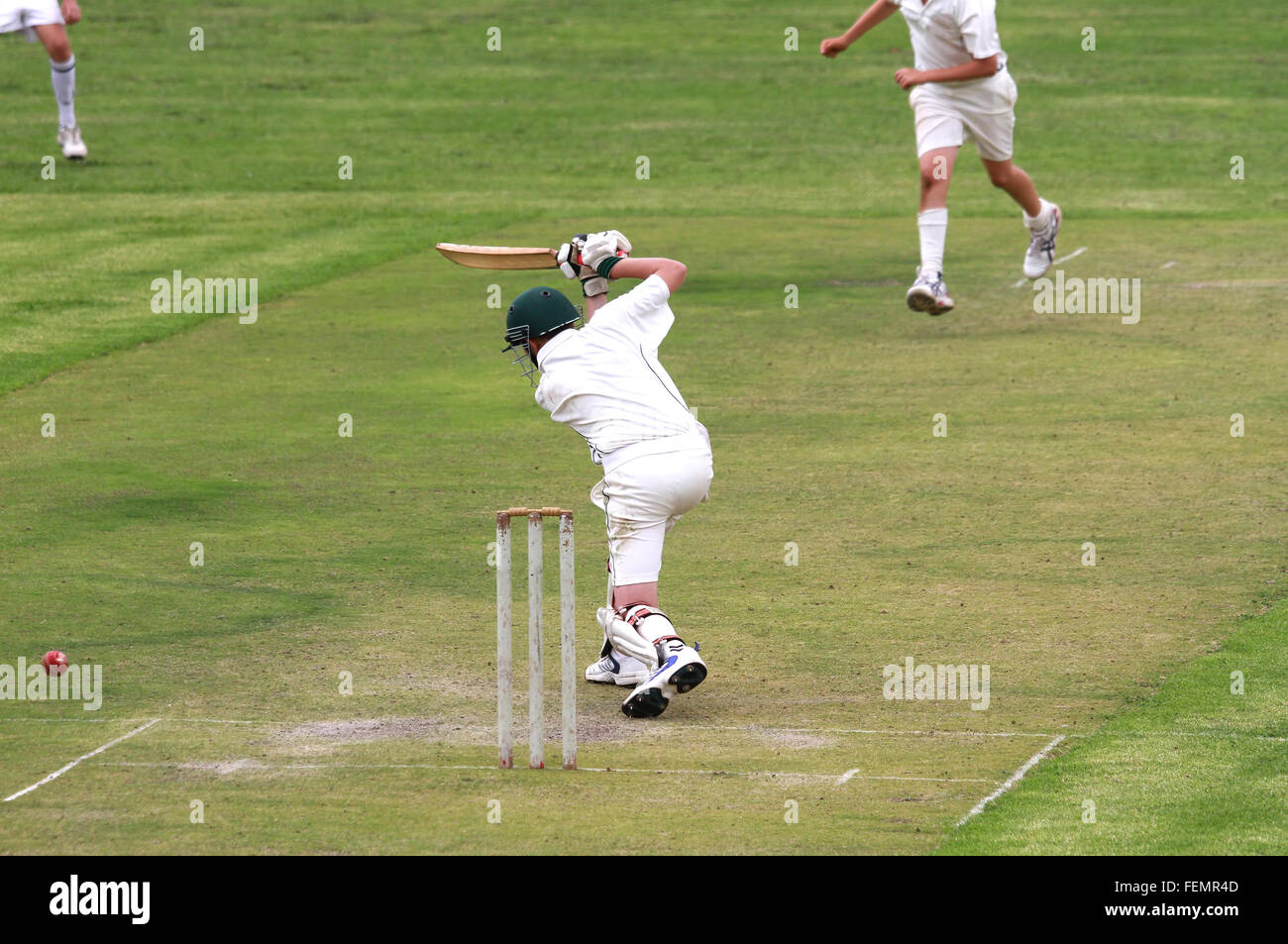 Un joven jugador de cricket o adolescente está conduciendo a una bola de críquet a través de las tapas. Foto de stock