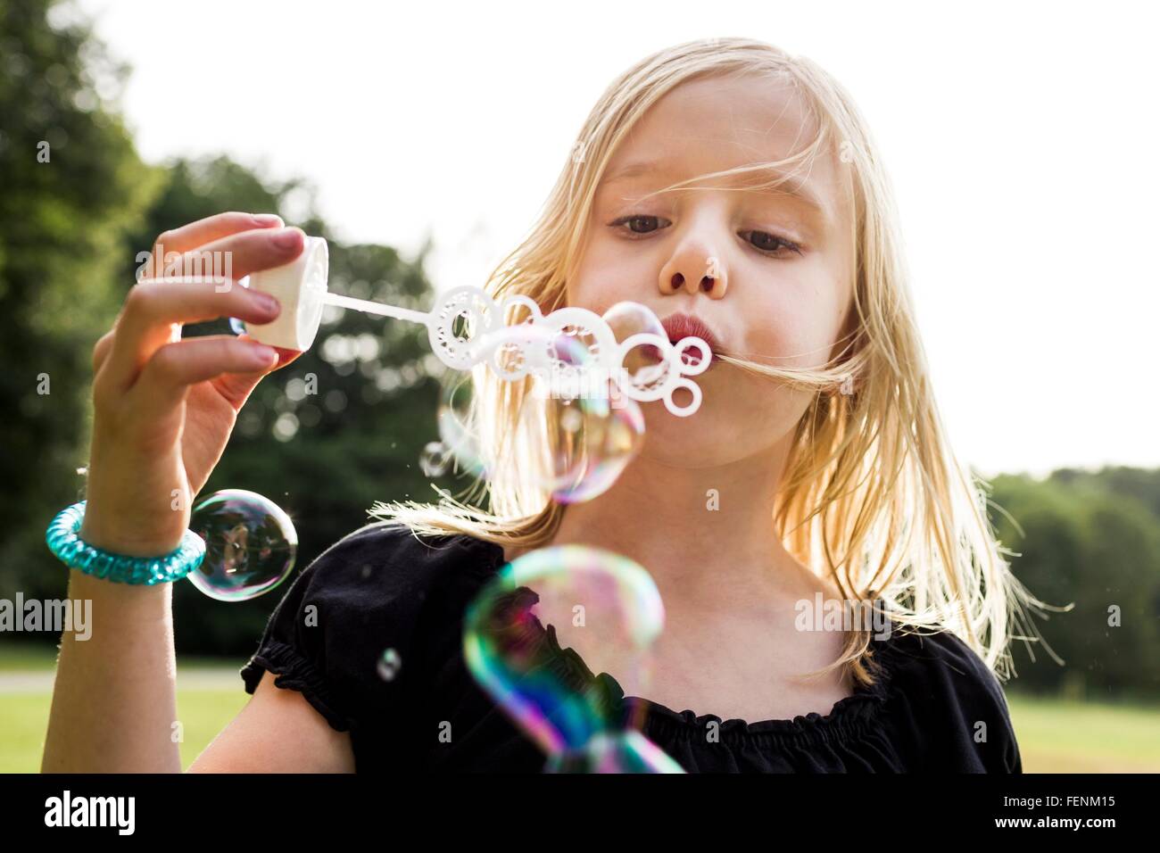 Retrato de linda niña soplando burbujas en el parque Foto de stock