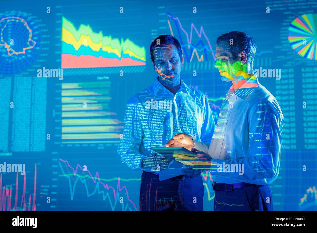 Empresarios en conversación con gráficos proyectados datos financieros Foto de stock