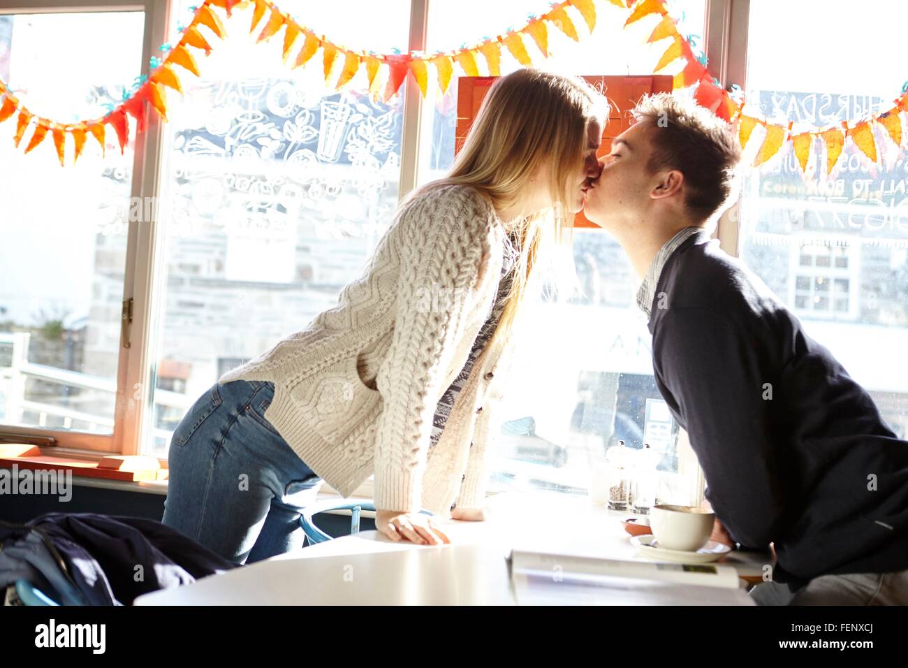 Romántico joven pareja besándose en mesita de café Foto de stock