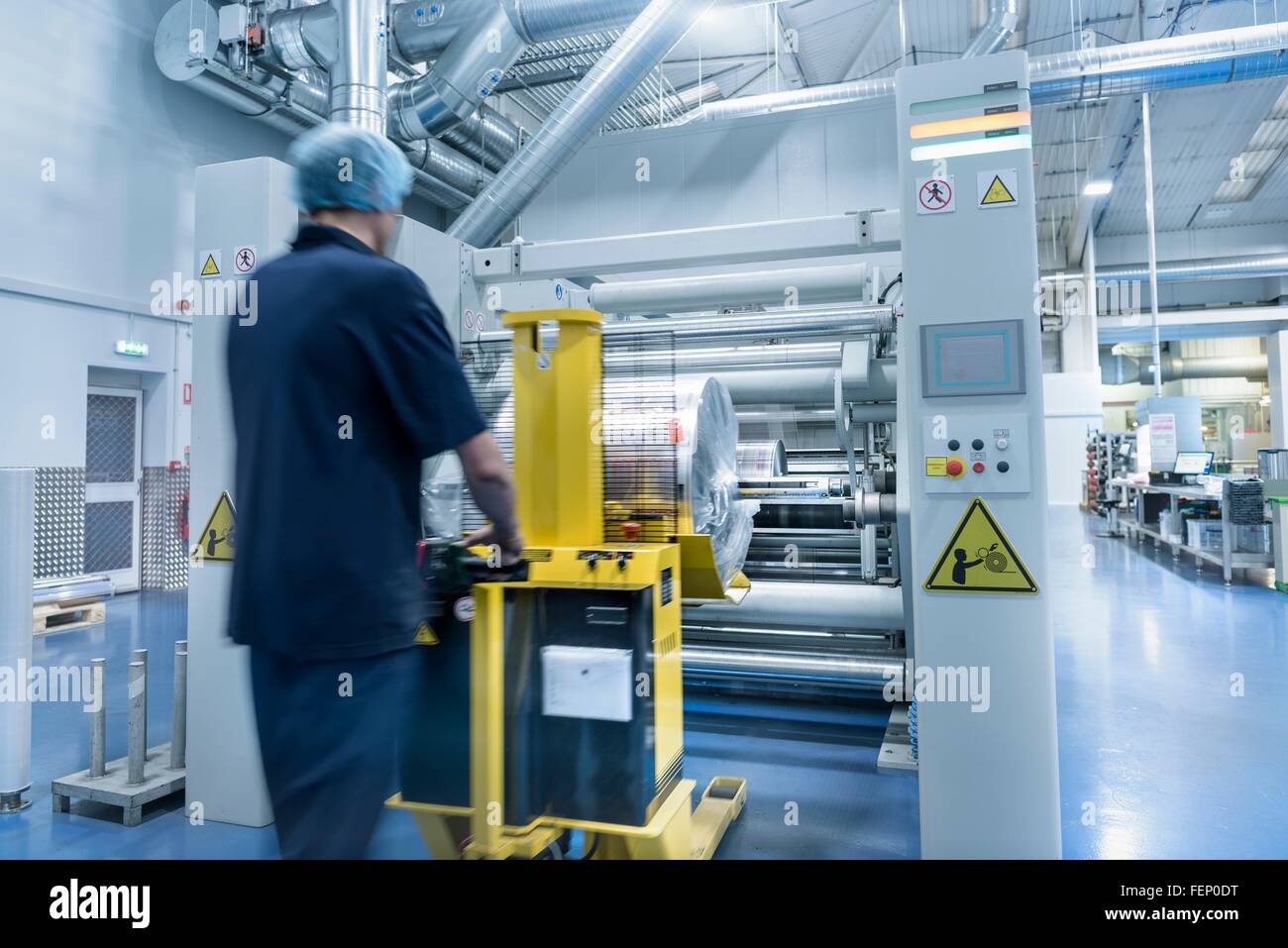 Trabajador descarga rollo impresa en la fábrica de impresión de embalaje de alimentos Foto de stock