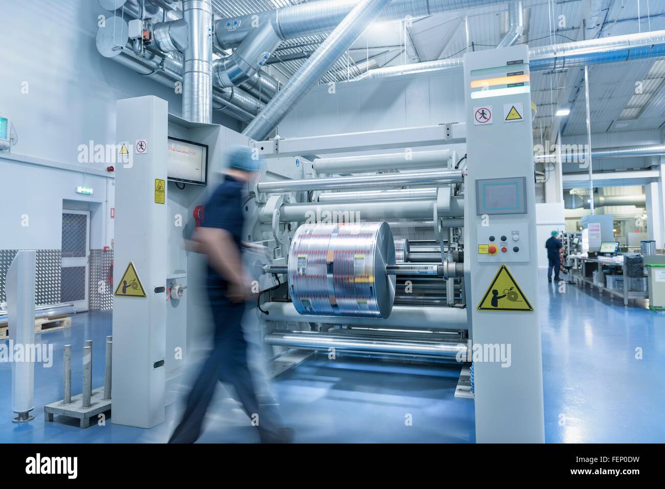 Trabajador descarga rollo impresa en la fábrica de impresión de embalaje de alimentos Foto de stock