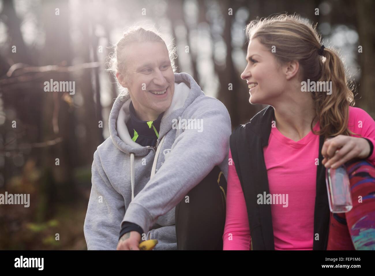 Par vistiendo ropa deportiva sosteniendo una botella de agua de sentarse  cara a cara sonriente Fotografía de stock - Alamy