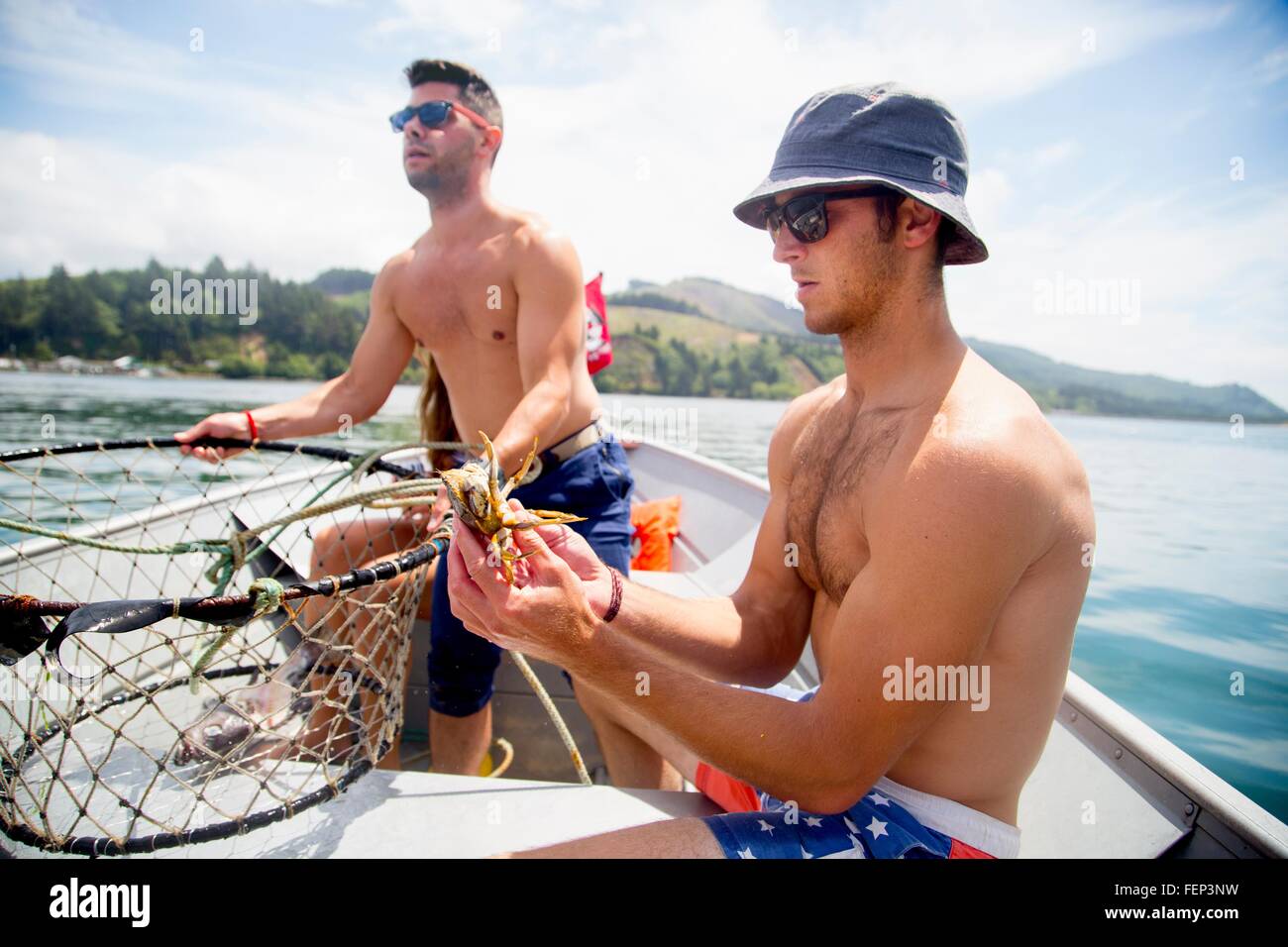 Mediados de los hombres adultos comprobando la trampa de cangrejo en barco de pesca, Nehalem Bay, Oregón, EE.UU. Foto de stock