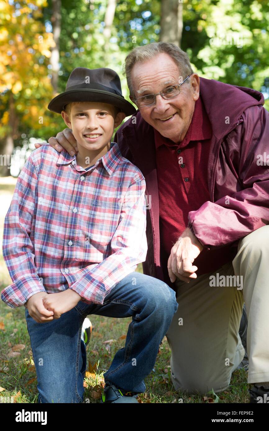 Retrato del hombre senior y nieto de rodillas en maderas Foto de stock