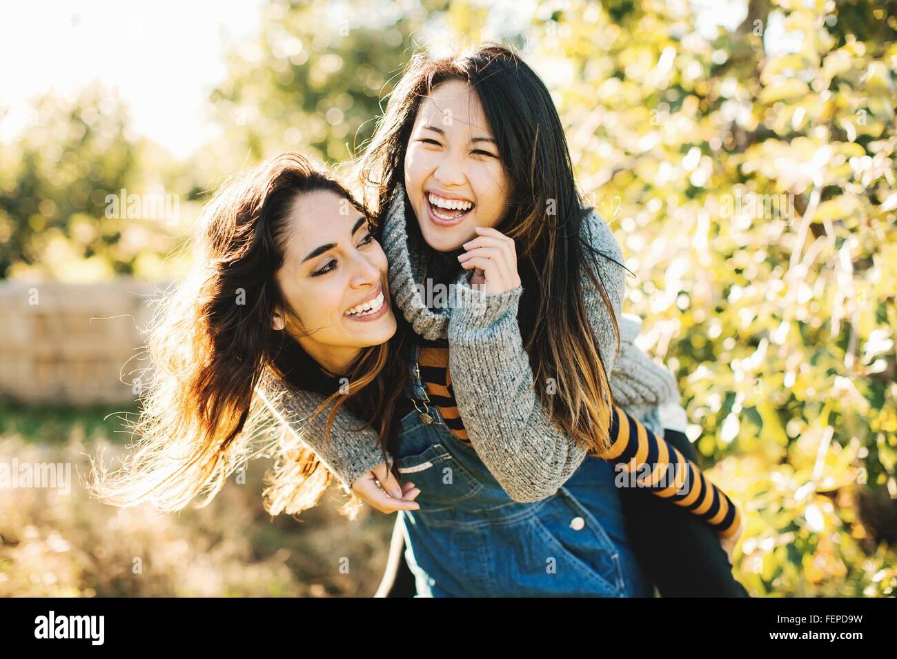 Mujer joven dando amigo piggyback ride, exteriores Foto de stock