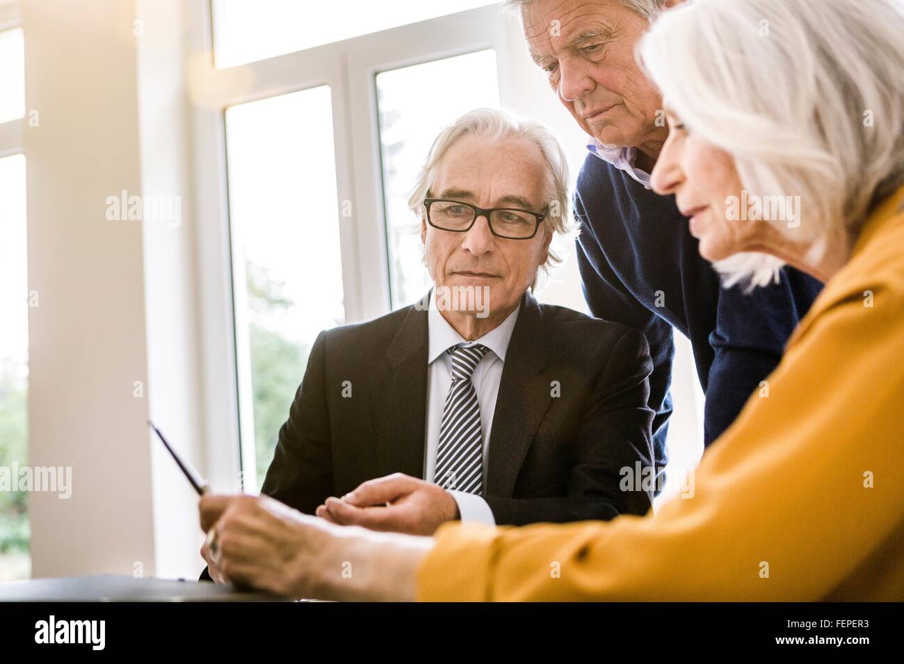 Adultos mayores en reunión de negocios discutiendo papeleo Foto de stock